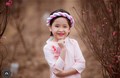 Bé gái 6 tuổi diện áo dài bên vườn đào