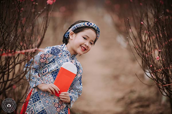 Bé gái 6 tuổi diện áo dài bên vườn đào